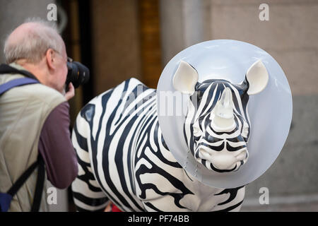 London, Großbritannien. 20. August 2018. Ein tourist Fotos' Gehen, Gehen, Weg, ein Nashorn gemalt von Mauro Perucchetti, in Covent Garden. 21 Nashörner sind in einer beliebten Lage in Central London, bildet der Tusk Rhino Trail, bis Welt Rhino Tag am 22. September das Bewusstsein für die schwere Bedrohung der Wilderei auf die Arten" überleben. Sie werden dann von Christie's am 9. Oktober versteigert werden Mittel für die Tusk Tierschutz Nächstenliebe anzuheben. Credit: Stephen Chung/Alamy Stockfoto