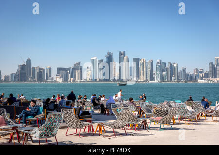 Doha, Katar - Jan 8 2018 - Einheimische und Touristen, eine Cafe Bar mit Doha Skyline im Hintergrund in einem blauen Himmel Tag, Doha in Katar Stockfoto