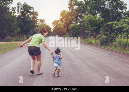 Mutter mit einer Hand seiner Tochter zu Fuß in den öffentlichen Park Stockfoto
