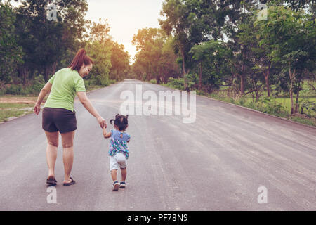 Mutter mit einer Hand seiner Tochter zu Fuß in den öffentlichen Park Stockfoto