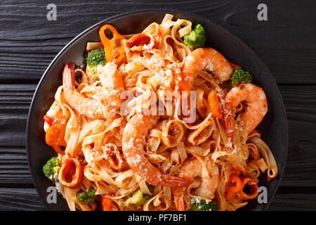 Rezept italienischer Pasta Bandnudeln mit Garnelen, Tintenfisch, Brokkoli, Käse mit Tomatensauce closeup auf einem Teller. Horizontal oben Ansicht von oben Stockfoto