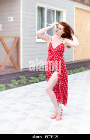 Junge Frau zu Fuß auf der Straße Freude glücklich lächelnd. Brunette im roten Kleid sunshine Lifestyle Stockfoto