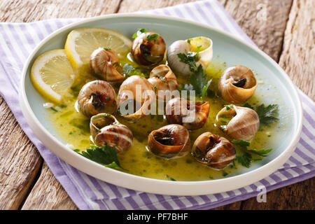 Würzige französische Schnecken, Escargot mit Butter, Petersilie, Zitrone und Knoblauch in der Nähe gekocht - bis auf einen Teller auf dem Tisch. Horizontale Stockfoto