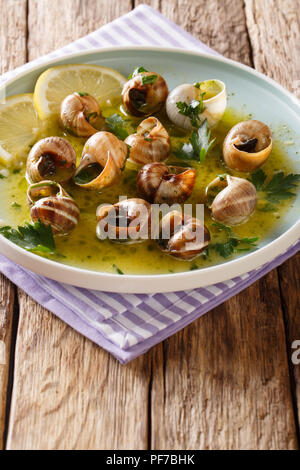 Französische Küche: Escargot mit Butter, Kräutern und Knoblauch close-up auf einem Teller auf dem Tisch. Vertikale Stockfoto