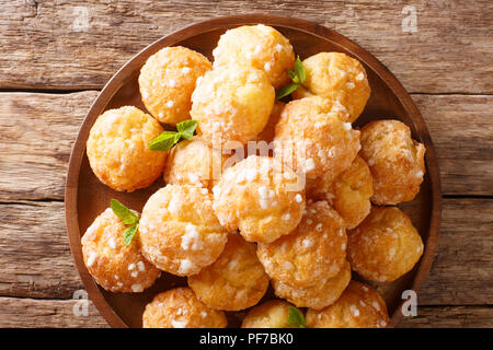 Französische Dessert chouquette Profiteroles mit perligen Zucker und Minze Nahaufnahme auf dem Tisch. Horizontal oben Ansicht von oben Stockfoto