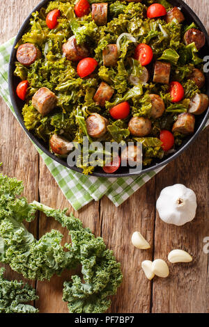 Gebratener Rotkohl Grünkohl mit Wurst, Tomaten und Parmesan auf einer Platte close-up auf den Tisch. Vertikal oben Ansicht von oben Stockfoto