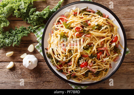 Italienisches Mittagessen Pasta mit Rotkohl Grünkohl, Speck, Tomaten und Parmesan closeup auf einem Teller. horizontal oben Ansicht von oben Stockfoto