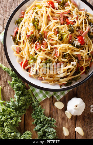 Pasta Linguine mit Kohl Kohl, Speck, Tomaten und Parmesan close-up auf einem Teller. Vertikal oben Ansicht von oben Stockfoto