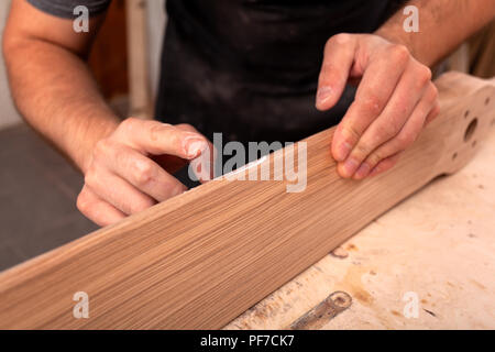 Close-up eine männliche Tischler in Arbeitskleidung Wiederherstellen eines Holz- mit einem Spachtel auf einer hölzernen Tisch Stockfoto
