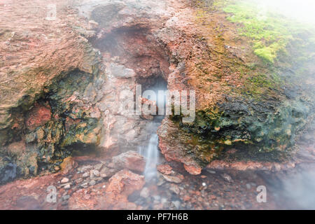 Nahaufnahme von Dampf Geysir in Deildartunguhver heiße Quellen in Island mit bewölkt Nebel Nebel lange glatte Exposition aus Red Rock bunte Höhle kochen Stockfoto