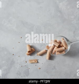 Knusprige Waffelröllchen liegen in einem Glas Schale - Dessert für Wein auf einem grauen Hintergrund. Stockfoto