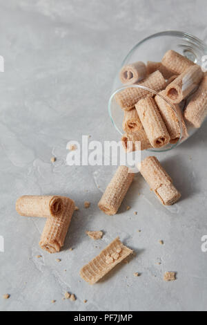 Knusprige Waffel Sticks in ein Glas Schale Dessert für Wein auf einem grauen Stein Tabelle. Stockfoto