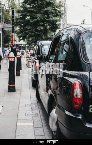 Reihe der schwarzen Taxis auf einer Seite der Straße in der Londoner City, berühmten Londoner Finanzviertel geparkt. Stockfoto