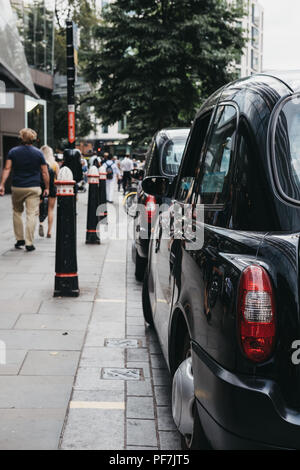 Reihe der schwarzen Taxis auf einer Seite der Straße in der Londoner City, berühmten Londoner Finanzviertel geparkt. Stockfoto