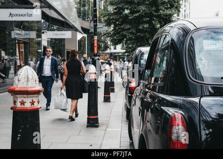 Reihe der schwarzen Taxis auf einer Seite der Straße in der Londoner City, berühmten Londoner Finanzviertel geparkt. Stockfoto