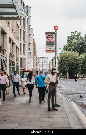 Mann sein Handy surfen beim Warten auf einen Bus auf dem Bus die St. Paul's Stop in der Stadt London, berühmten Londoner Financial District. Stockfoto