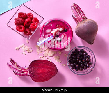 Gesunde Smoothies aus Rüben, Himbeeren, schwarzen Johannisbeeren und Mandelflocken auf einem Duplex blau rosa Papier Hintergrund gekocht. Stockfoto