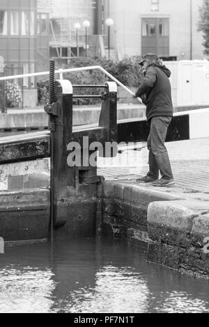 Schwarz-weiß-Bild eines Mannes Wicklung der Mechanismus Schleuse am Schloss in die City Road Becken, Islington, London, UK zu öffnen. Stockfoto