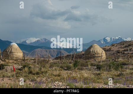 Traditionelle kirgisische Jurten mit Schnee bedeckte Berge im Hintergrund. In der Nähe von Bokonbayevo, Kirgisistan. Stockfoto