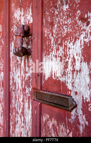 Klopfer und eine Mailbox im Namen 'Mr Le curé' auf einer hölzernen Tür mit abblätternder Farbe, Frankreich Stockfoto