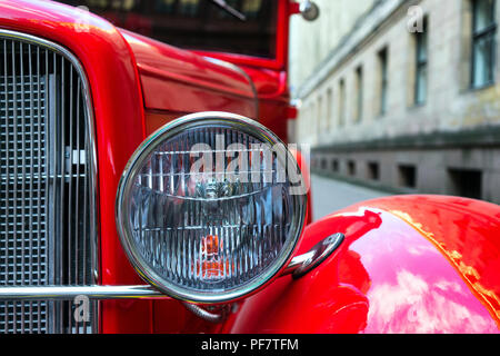 Scheinwerfer für Oldtimer rotes Auto auf einem Hintergrund der Altstadt Stockfoto