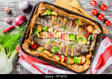Forelle Fisch gebacken mit Kartoffeln, Broccoli, Zitronen, Tomaten, Ansicht von oben Stockfoto