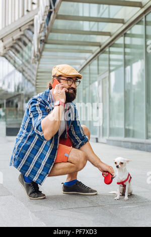 Dunkle Bärtigen schwarzhaarige Mann am Telefon sprechen beim Gehen Stockfoto