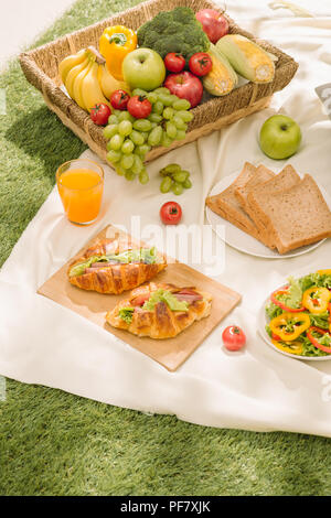 Gesunde Ernährung und Zubehör outdoor Sommer oder Frühling Picknick Picknick Weidenkorb mit frischem Obst, Brot und ein Glas frischen Orangensaft in t Stockfoto