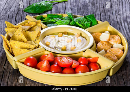 Gesunde hausgemachte köstliche würzige Hummus mit Karotten, Sellerie, Spinat, Ingwer, in Scheiben geschnitten Kalk, natives Olivenöl, Pinienkernen und Fladenbrot, zu Stockfoto