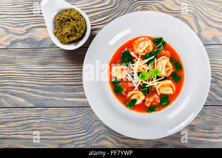 Tortellini Suppe mit italienischer Wurst, Spinat, Tomaten, Parmesankäse, Pesto - Sauce Stockfoto