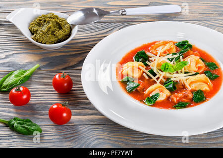 Tortellini Suppe mit italienischer Wurst, Spinat, Tomaten, Parmesankäse, Pesto - Sauce Stockfoto