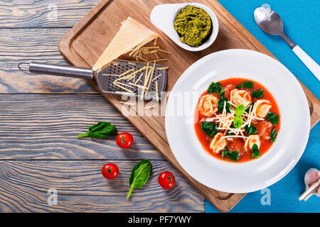Tortellini Suppe mit italienischer Wurst, Spinat, Tomaten, Parmesankäse, Pesto - Sauce Stockfoto