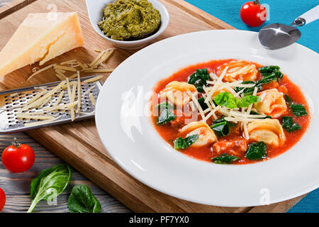 Tortellini Suppe mit italienischer Wurst, Spinat, Tomaten, Parmesankäse, Pesto - Sauce Stockfoto