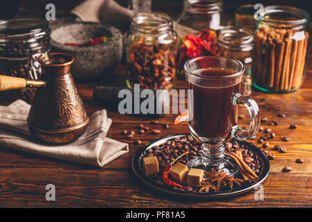 Cezve und Tasse Kaffee auf Metallplatte, die mit Getreide, Zucker und andere Gewürze auf Holzbrett. Stockfoto