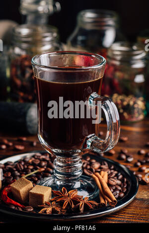 Tasse Kaffee auf Metallplatte mit Bohnen, raffiniertem Zucker und Zimtstange, Anis und Chili. Stockfoto