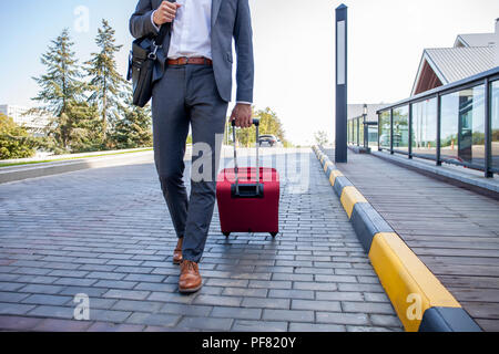 Geschäftsmann zu Fuß von Hotel Lobby. In voller Länge Porträt der jungen Executive mit einem Koffer. Stockfoto