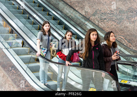 Tysons Corner, USA - 26. Januar 2018: Viele junge Mädchen im Teenageralter gehen hinunter Rolltreppe in Shopping Mall, Virginia Stockfoto