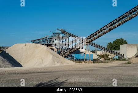 Förderband über Haufen von Kies auf blauen Himmel bei einem industriellen Zementwerk. Stockfoto