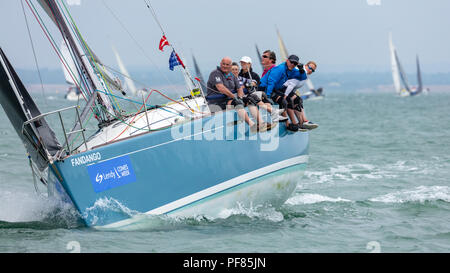 Den Solent, Hampshire, UK; 7. August 2018, Blick Richtung Bogen der Betuchten Yacht Racing in Cowes Week Regatta mit Crew sitzt auf der Seite des Bootes Stockfoto