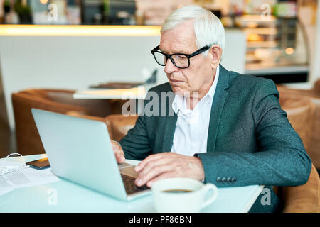 Senior Geschäftsmann mit Laptop im Cafe Stockfoto