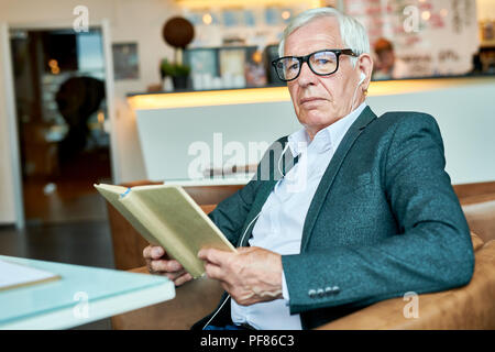 Nachdenklich älterer Mann Lesung buchen Sie im Cafe Stockfoto