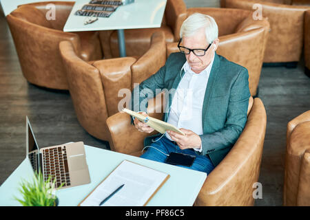 Moderne älterer Mann Lesung buchen Sie im Cafe Stockfoto