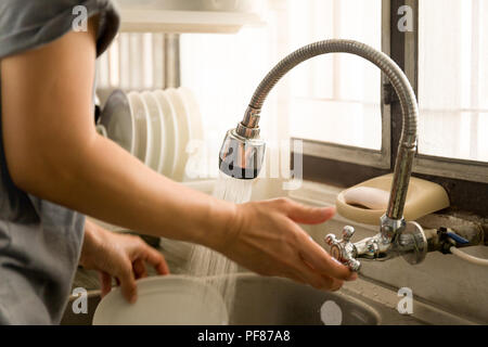 Woman's Trun auf Leitungswasser machen den Abwasch in der Küche zu Hause. Stockfoto