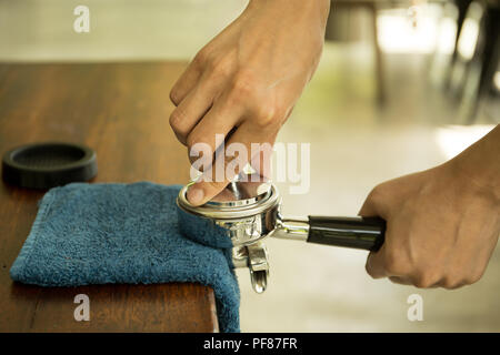 Barista drücken gemahlenen Kaffee in portafilter mit Stampfer mit blauem Tuch auf den Tisch Stockfoto