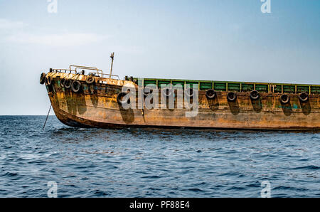 Schönes Bild von einem Verankerten Zubringer Schiff, Ladung in loser Schüttung ab Hafen der Stadt zum Mutterschiff am Anchorage verankert. Sieht ähnlich aus wie Stockfoto