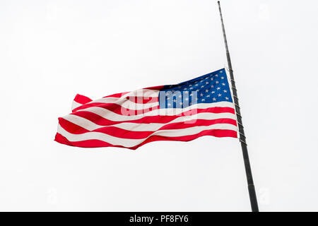 Usa Flagge zum halben Angestellten Winken gegen den grauen Himmel Stockfoto