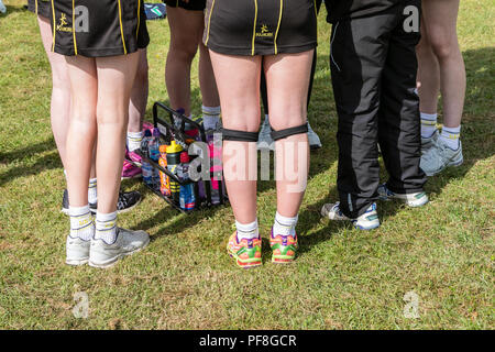 Die Hälfte der Zeit Team sprechen für eine Mädchenschule netball Team, den Trainer zu Ihnen spricht. Nur Beine und Turnschuhe sind sichtbar Stockfoto