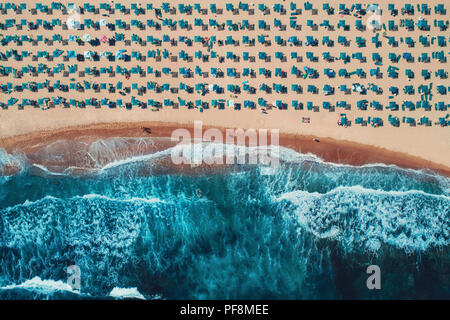 Antenne top Aussicht auf den Strand. Regenschirme, Sand und Meer Wellen Stockfoto