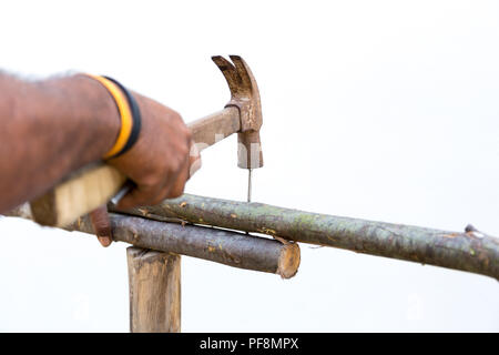 Man Hände Nägel mit dem Hammer auf Holz im Außenbereich einen Zaun Stockfoto