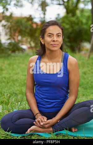 Junge Frau sitzen auf Yoga Matte in natürlichen Sommer Park Hintergrund Stockfoto